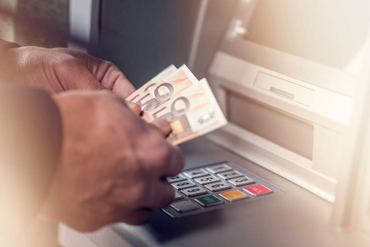 Un hombre con tres billetes de 50 euros en un cajero de un banco