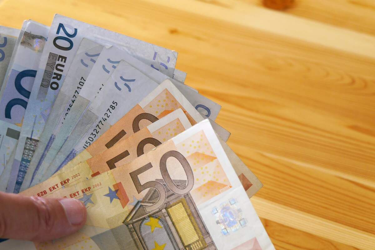 Banknotes of 50 and 20 euros in a hand, on a wooden table Banknotes of 50 and 20 euros in a hand, on a wooden table