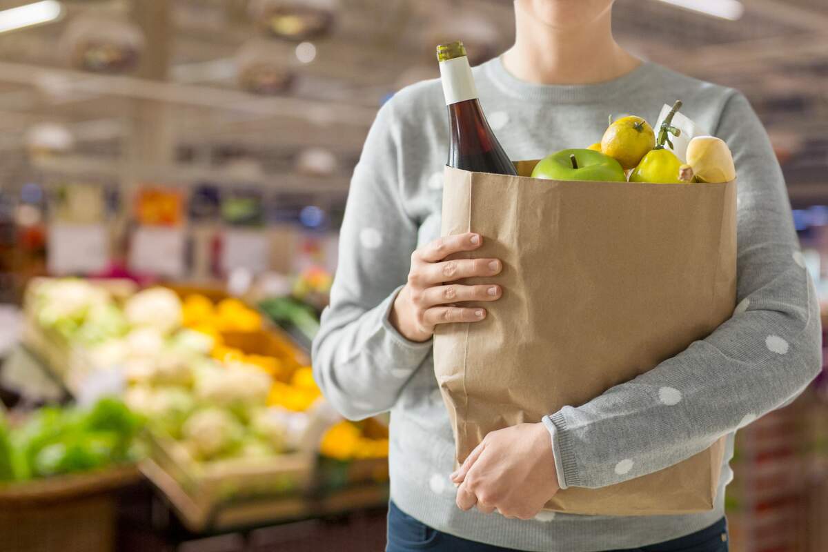 Hombre en un supermercado con una bolsa de papel llena de compra