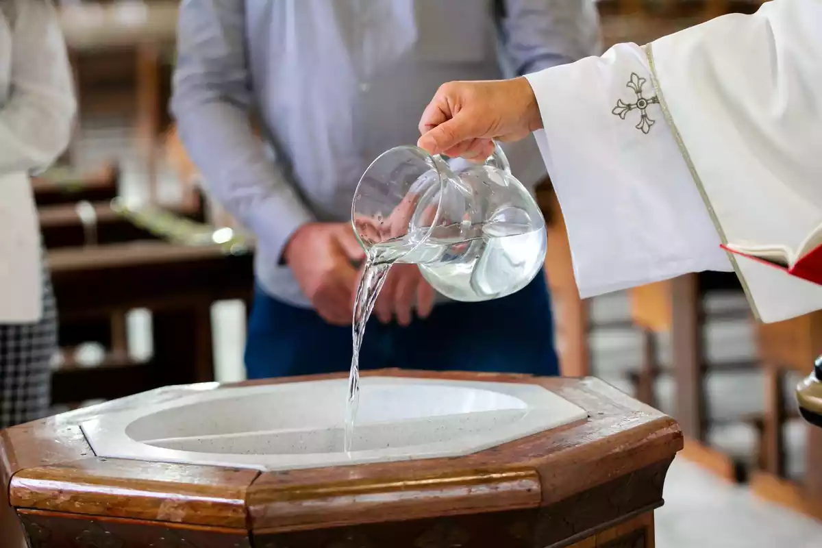 Cura echando agua a una pila bautismal Cura echando agua a una pila bautismal