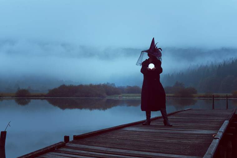 A witch holding a magic ball in a lake