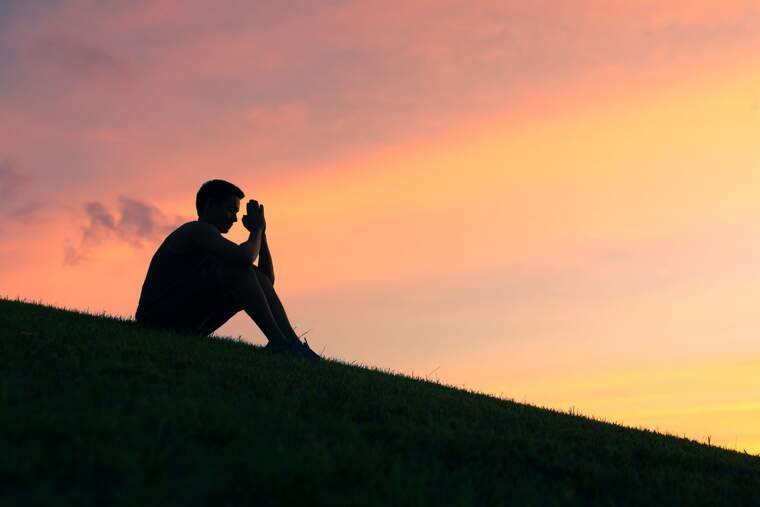 Boy praying during sunset