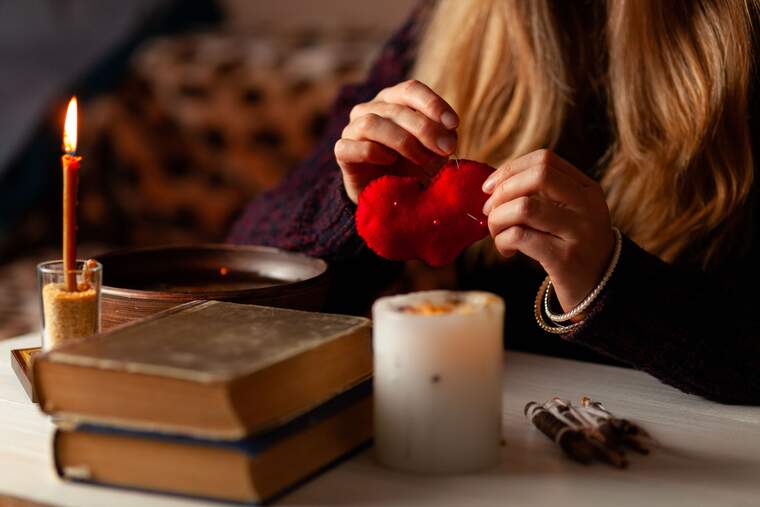 Witch casting a love spell with a red heart in her hands
