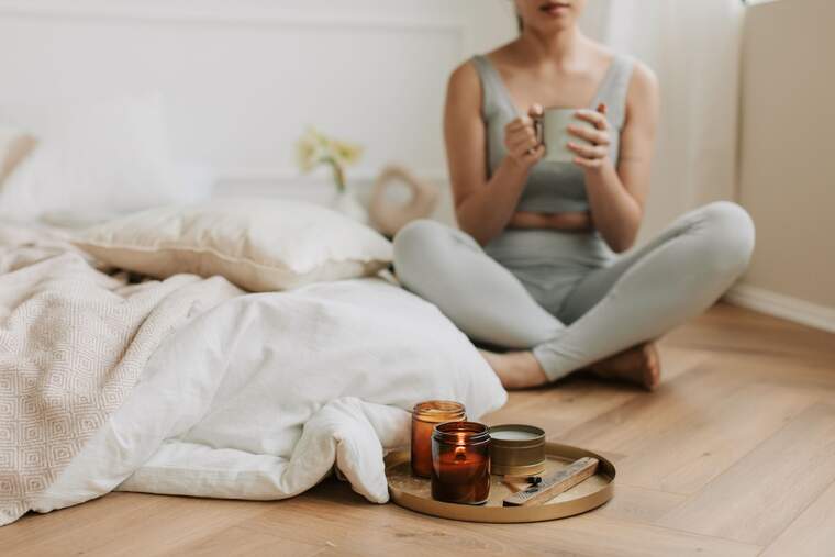 Mujer con una taza de té sentada en el suelo de su habitación
