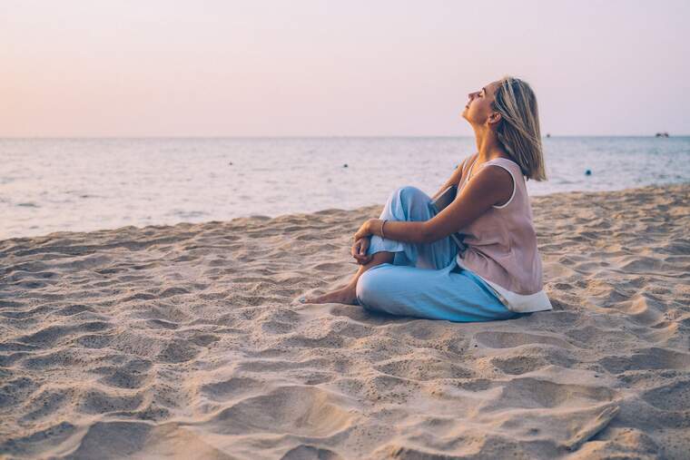 Mujer meditando en la arena de la playa