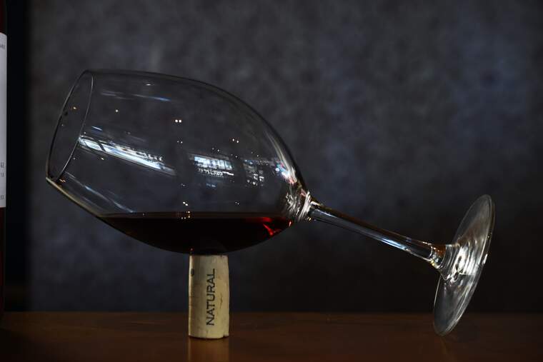 Copa de vi negre tombada sobre un tap de suro