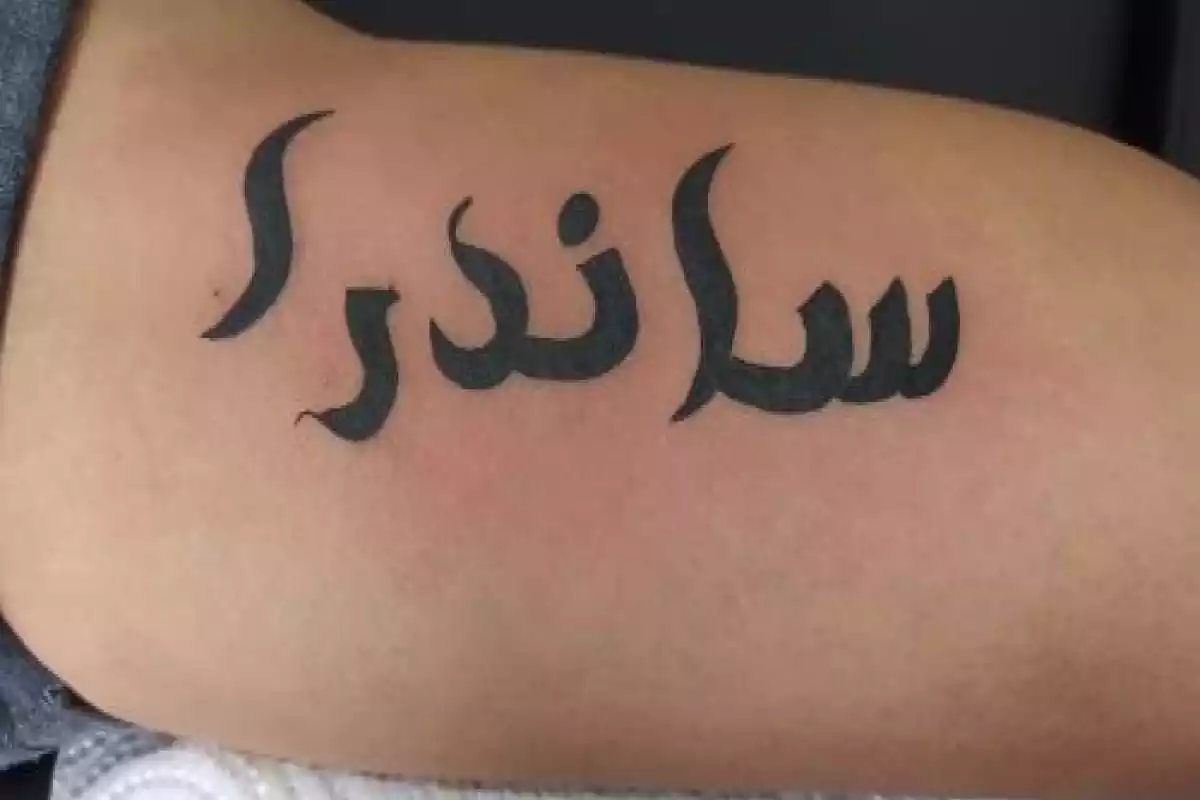 Diseño tatuaje en el brazo con un nombre en letras árabes en negro Diseño tatuaje en el brazo con un nombre en letras árabes en negro