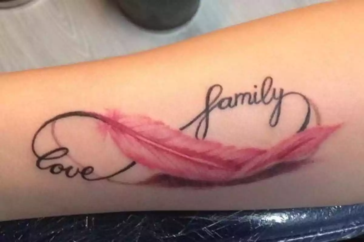 Foto de un brazo con un tatuaje del símbolo del infinito formado con las palabras 'family' y 'love' y una pluma roja Foto de un brazo con un tatuaje del símbolo del infinito formado con las palabras 'family' y 'love' y una pluma roja
