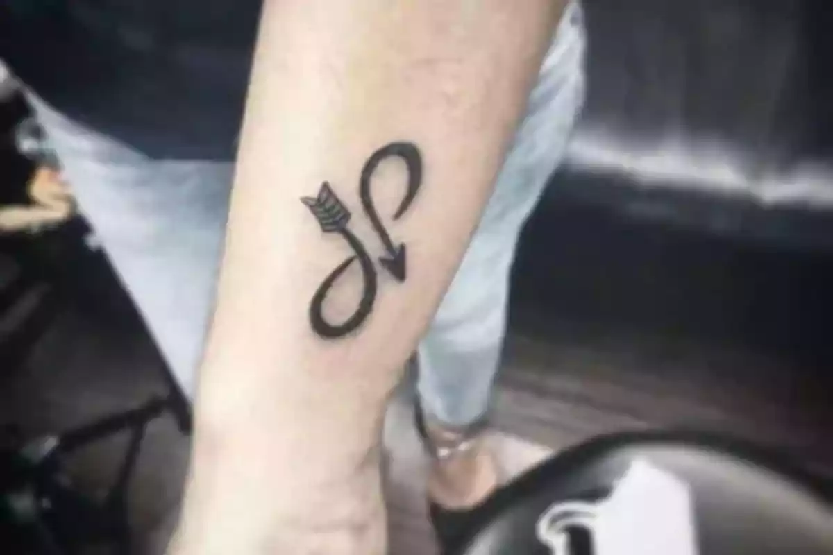 Foto de un brazo con un tatuaje en negro del símbolo de infinito a partir de una flecha Foto de un brazo con un tatuaje en negro del símbolo de infinito a partir de una flecha