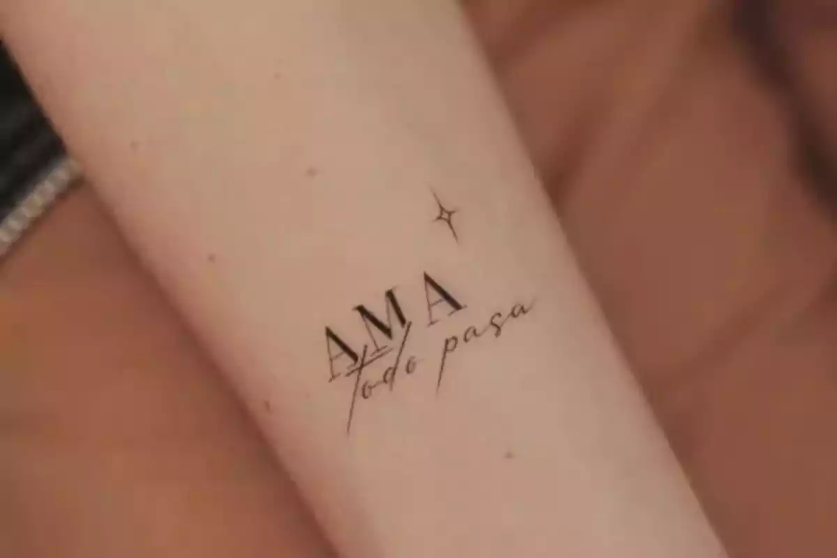 Foto de un brazo recortada en la que aparece un tatuaje en tinta negra de la frase 'Ama todo pasa' junto a una estrella Foto de un brazo recortada en la que aparece un tatuaje en tinta negra de la frase 'Ama todo pasa' junto a una estrella