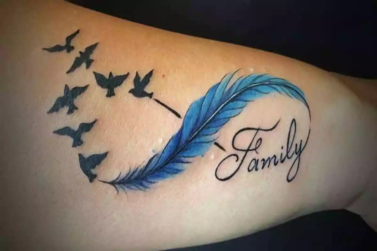 Foto de un tatuaje en primer plano de un símbolo de infinito con unos pájaros y con una pluma además de la palabra Family Foto de un tatuaje en primer plano de un símbolo de infinito con unos pájaros y con una pluma además de la palabra Family