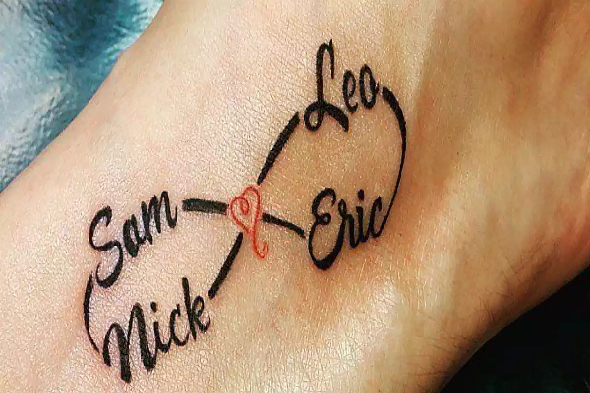 Foto de un tatuaje sobre la piel en primer término con un símbolo de infinito formado por cuatro nombres y un corazón rojo en el centro Foto de un tatuaje sobre la piel en primer término con un símbolo de infinito formado por cuatro nombres y un corazón rojo en el centro