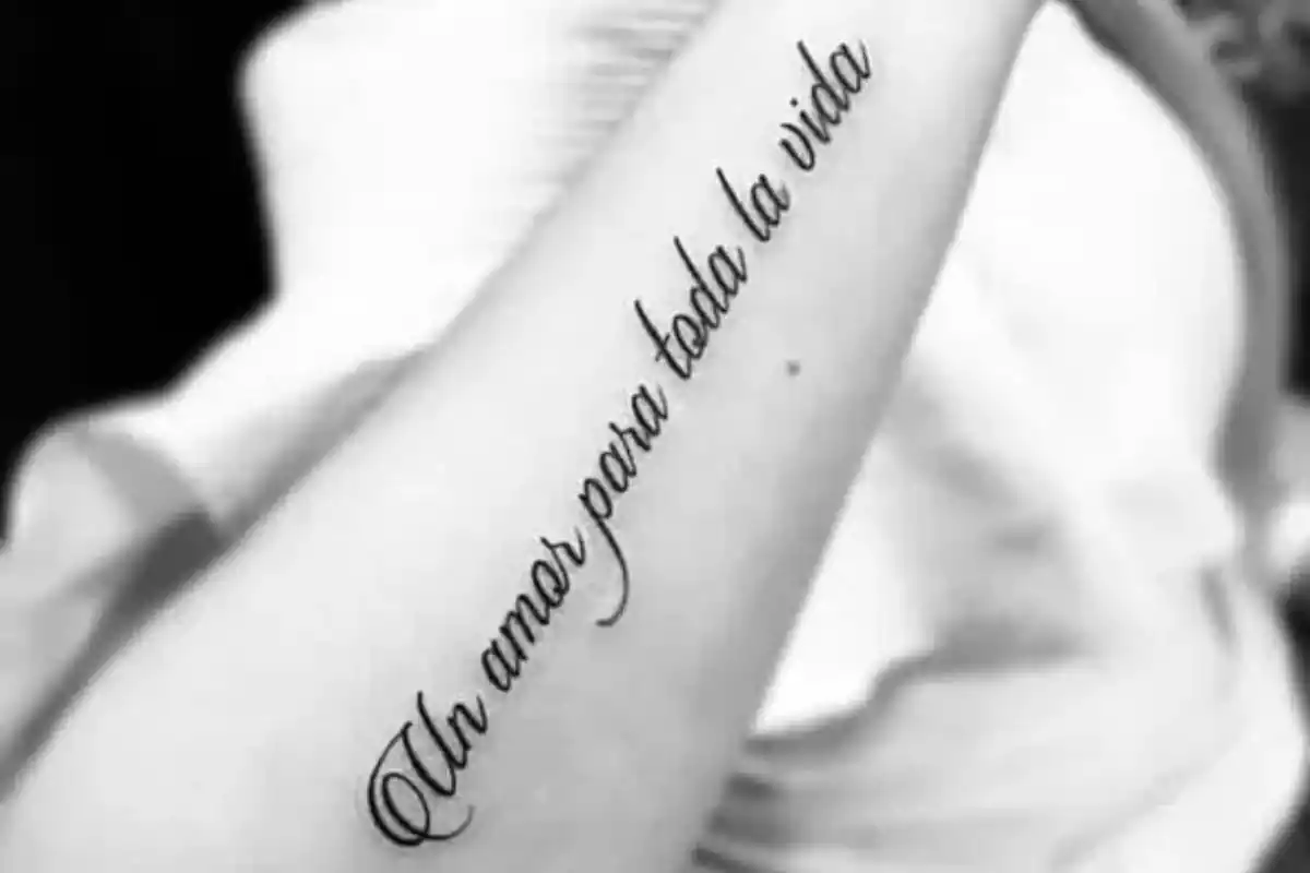 Foto en blanco y negro de un brazo con la frase tatuada 'Un amor para toda la vida' Foto en blanco y negro de un brazo con la frase tatuada 'Un amor para toda la vida'