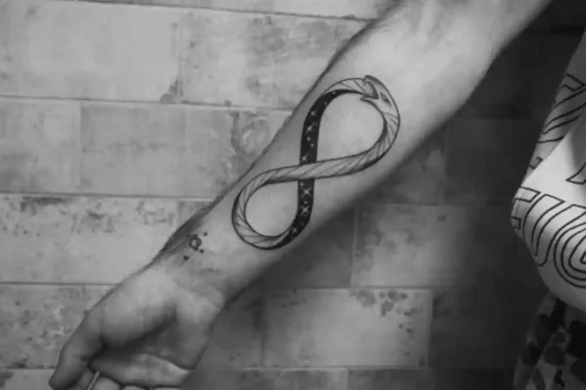 Foto en blanco y negro de un brazo con un tatuaje del símbolo de infinito formado por una serpiente Foto en blanco y negro de un brazo con un tatuaje del símbolo de infinito formado por una serpiente