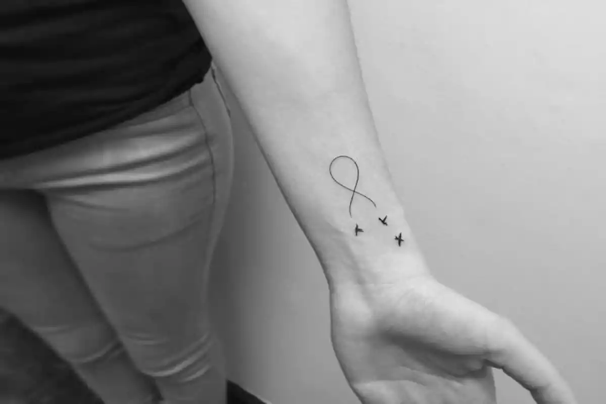 Foto en blanco y negro de un brazo con un tatuaje minimalista de un símbolo de infinito con tres X Foto en blanco y negro de un brazo con un tatuaje minimalista de un símbolo de infinito con tres X