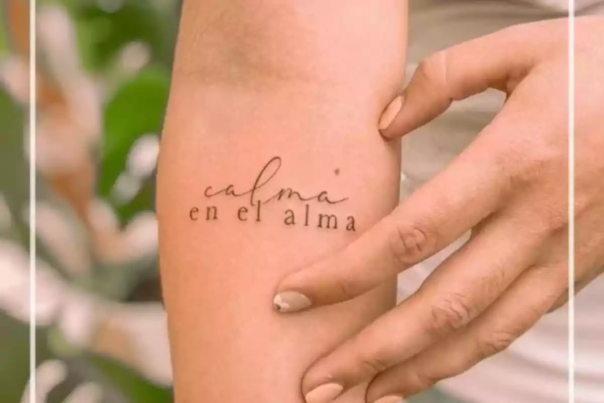 Foto recortada de un brazo en el que aparece una mano en torno a un tatuaje con la frase 'Calma en el alma' Foto recortada de un brazo en el que aparece una mano en torno a un tatuaje con la frase 'Calma en el alma'