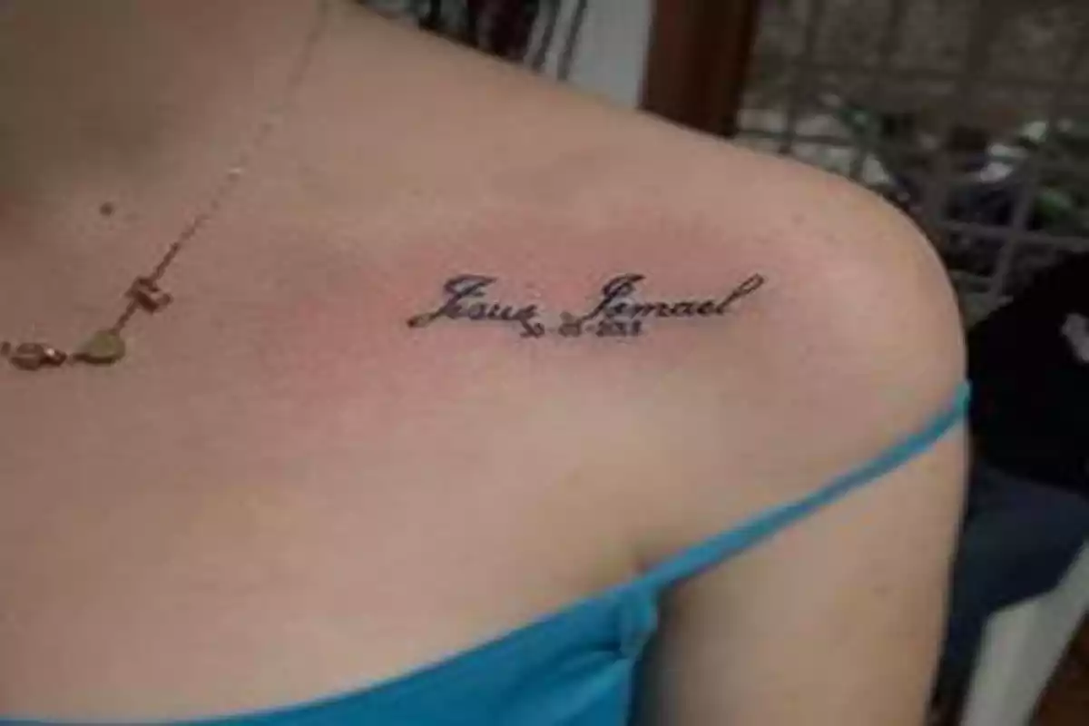 Hombro de mujer con un tatuaje del nombre Jesús Manuel y una fecha Hombro de mujer con un tatuaje del nombre Jesús Manuel y una fecha