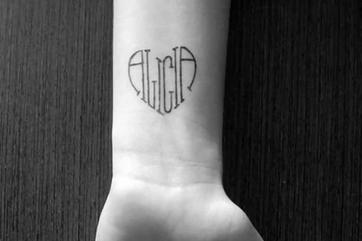 Tatuaje de nombre Alicia en forma corazón sobre muñeca en foto en blanco y negro Tatuaje de nombre Alicia en forma corazón sobre muñeca en foto en blanco y negro