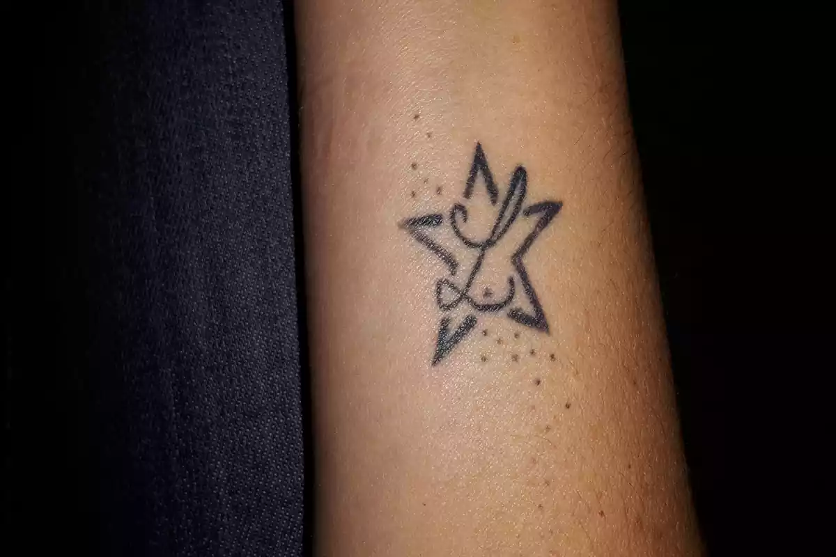 Tatuaje de una inicial con una estrella en una muñeca-antebrazo Tatuaje de una inicial con una estrella en una muñeca-antebrazo