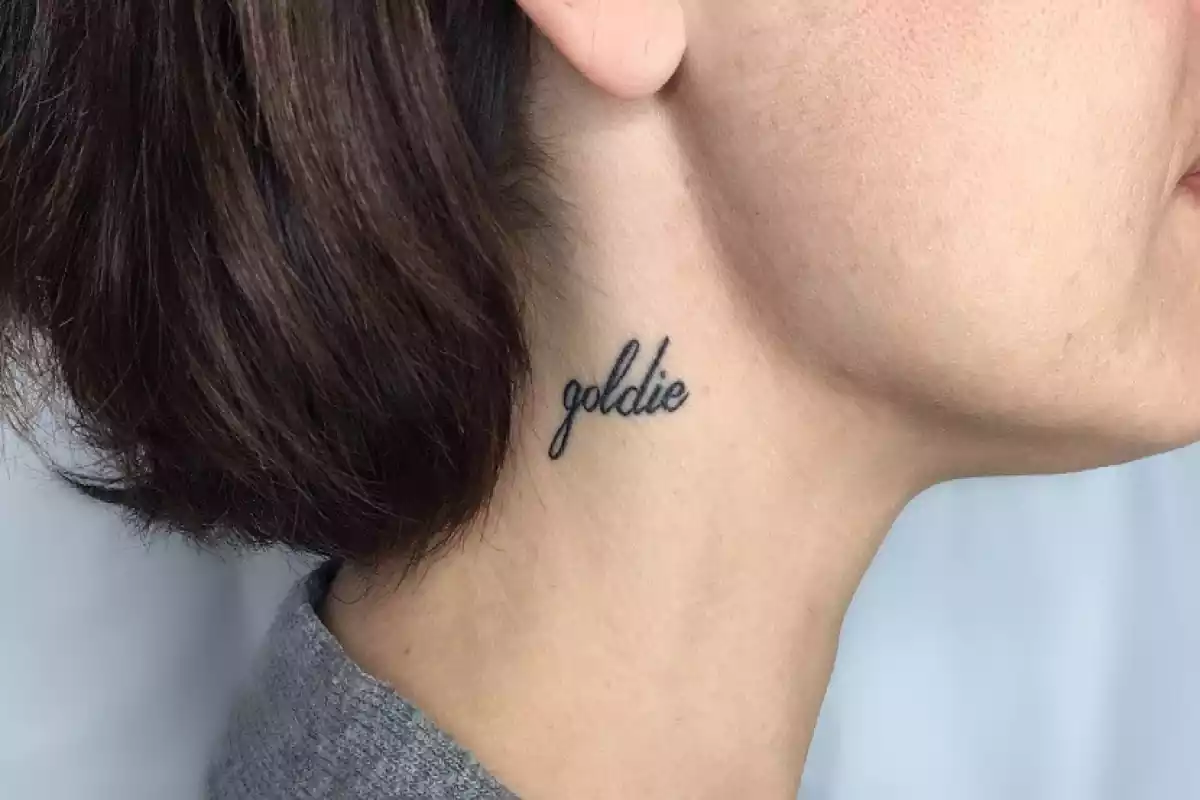 Tatuaje del nombre Goldie en el cuello de una mujer Tatuaje del nombre Goldie en el cuello de una mujer