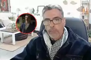 Hombre de cabello canoso y gafas sentado en una oficina con decoración moderna y una planta sobre la mesa, con un recuadro circular mostrando a la misma persona en otro entorno.