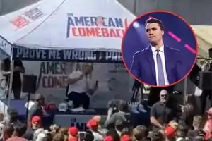 Un hombre en un evento al aire libre bajo una carpa con el texto American Comeback rodeado de una multitud, con un recuadro que muestra a un hombre de traje y corbata