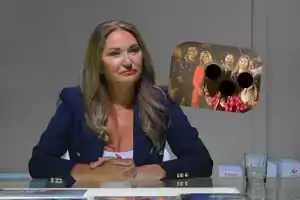 Mujer sentada en una mesa con las manos entrelazadas y una expresión seria, al fondo aparece una foto de grupo con dos rostros cubiertos por círculos negros